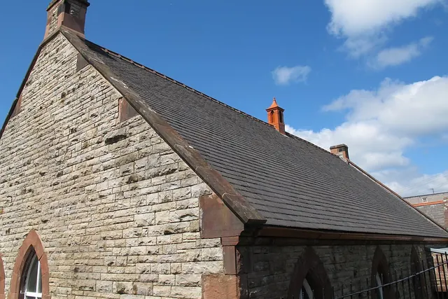 Toiture en ardoise sur un bâtiment de pierre, sous un ciel bleu
